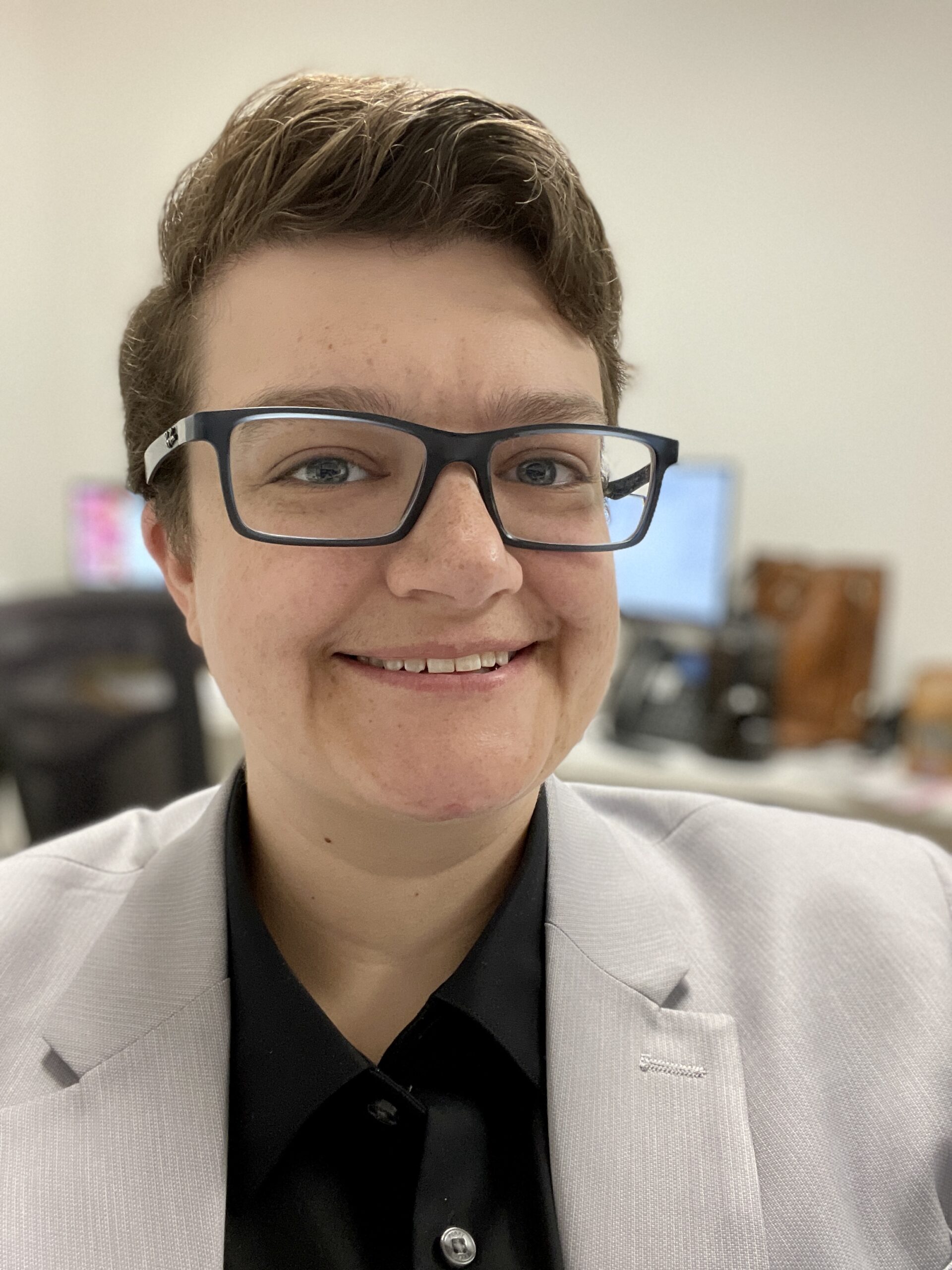 Close-up portrait of person smiling, seated in a computer lab.